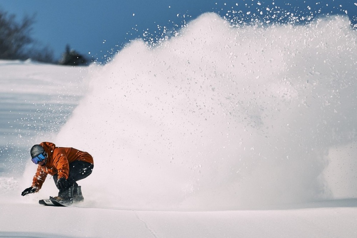 Snowboarder carving through deep powder spray at Appi Kogen, Japan