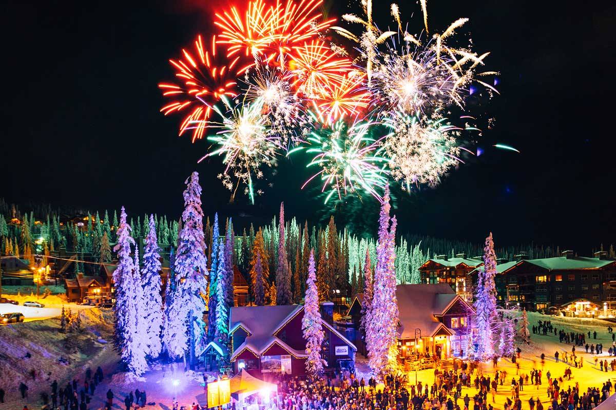 Fireworks over Big White's illuminated village, crowds gathered below