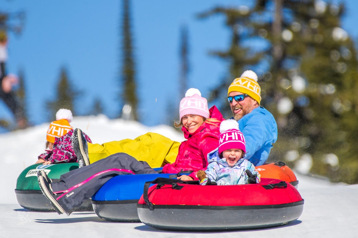 Family snow tubing together at Big White, wearing Big White toques