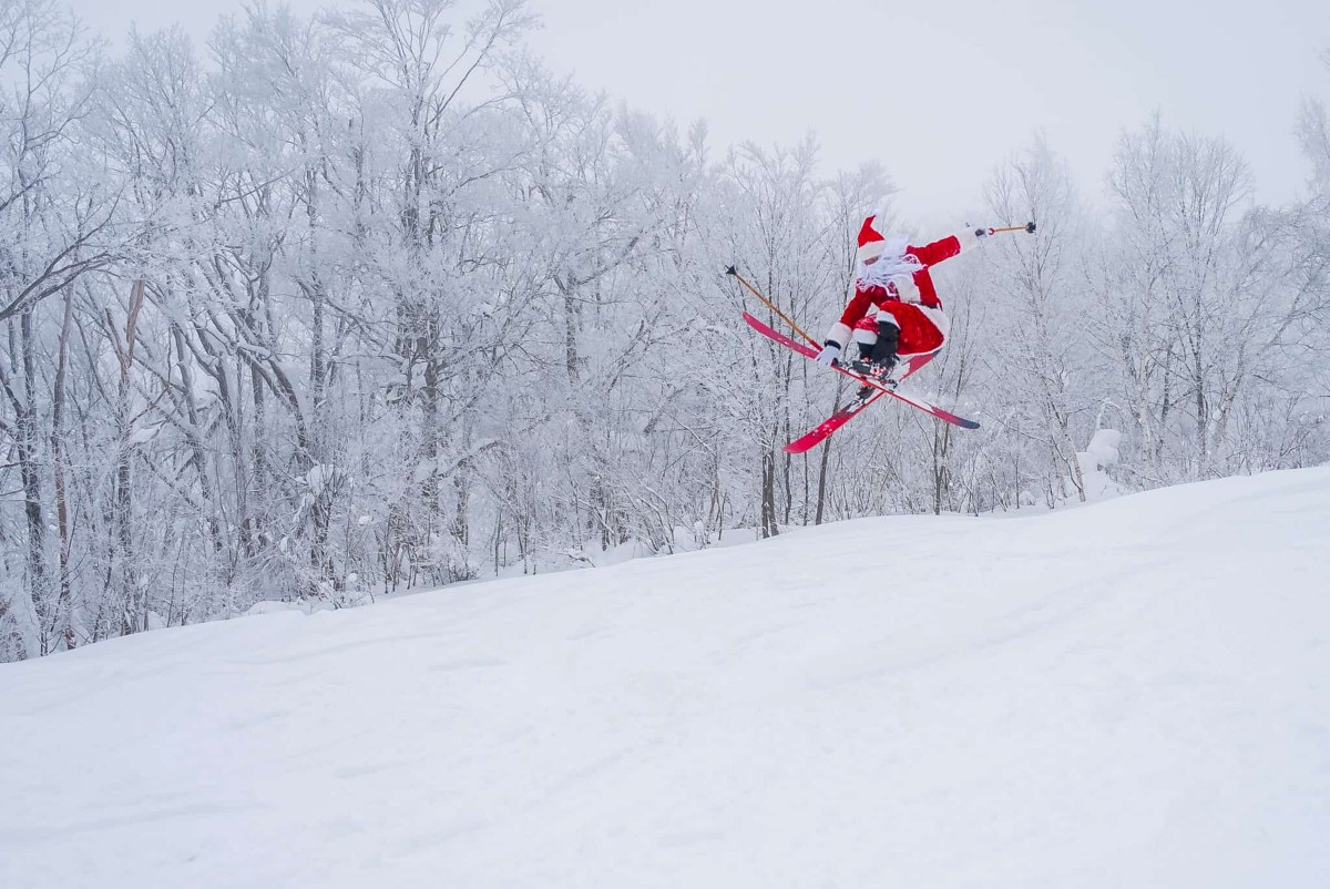 Skier in a Santa costume performing a jump on a snowy run in Japan