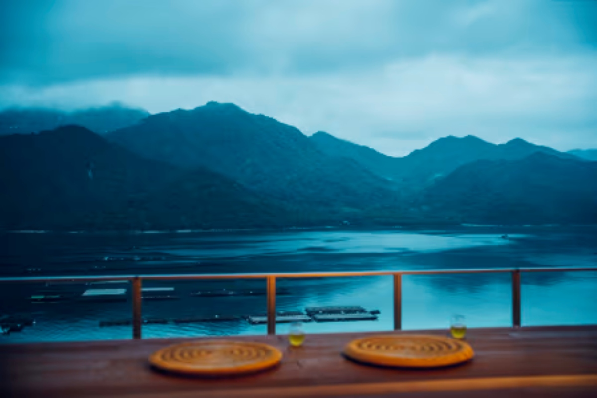 Drinks and woven coasters set on the terrace at KAI Miyajima, overlooking the sea