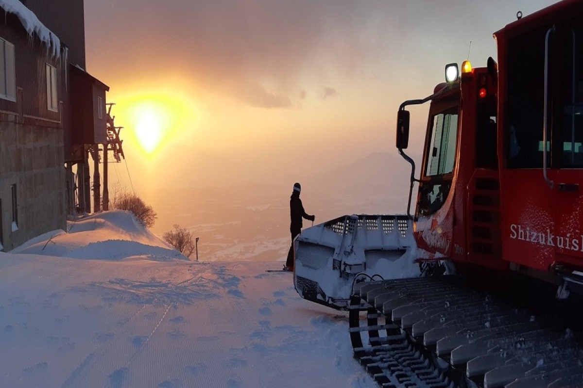 Snowcat and skier watching sunrise at Shizukuishi, Japan