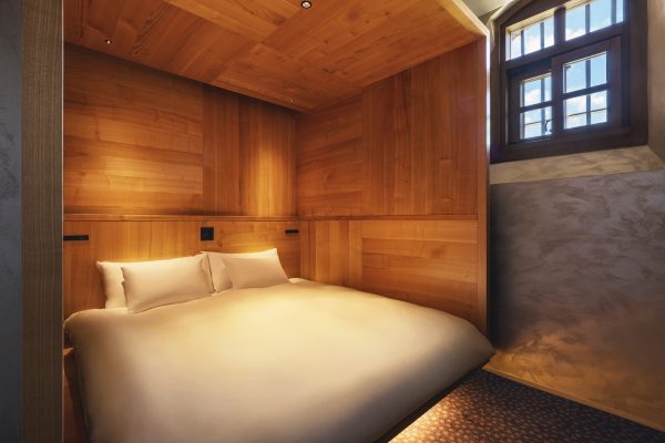 Bed built into a wooden box structure inside a HOSHINOYA Nara Prison suite, original window visible