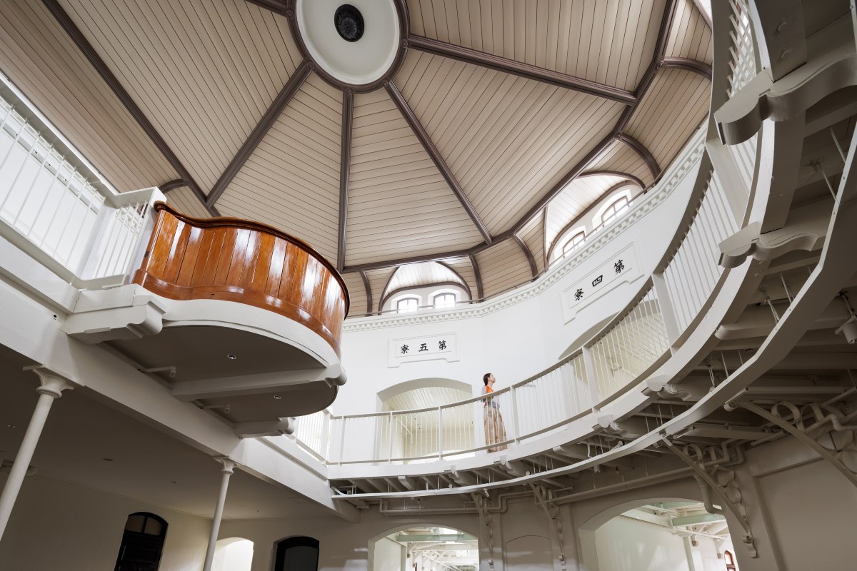 Guest standing on an upper walkway beneath the domed ceiling of the central rotunda at Nara Prison
