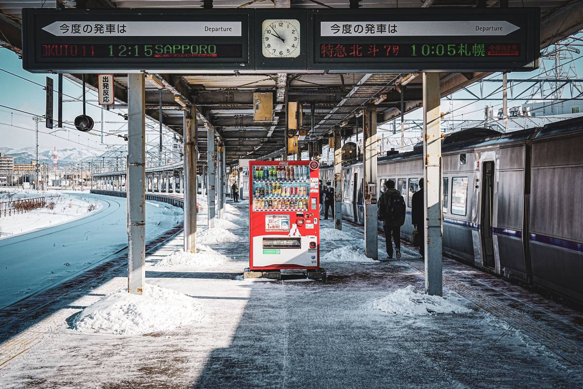 A snowy Japanese station platform with a train to Sapporo